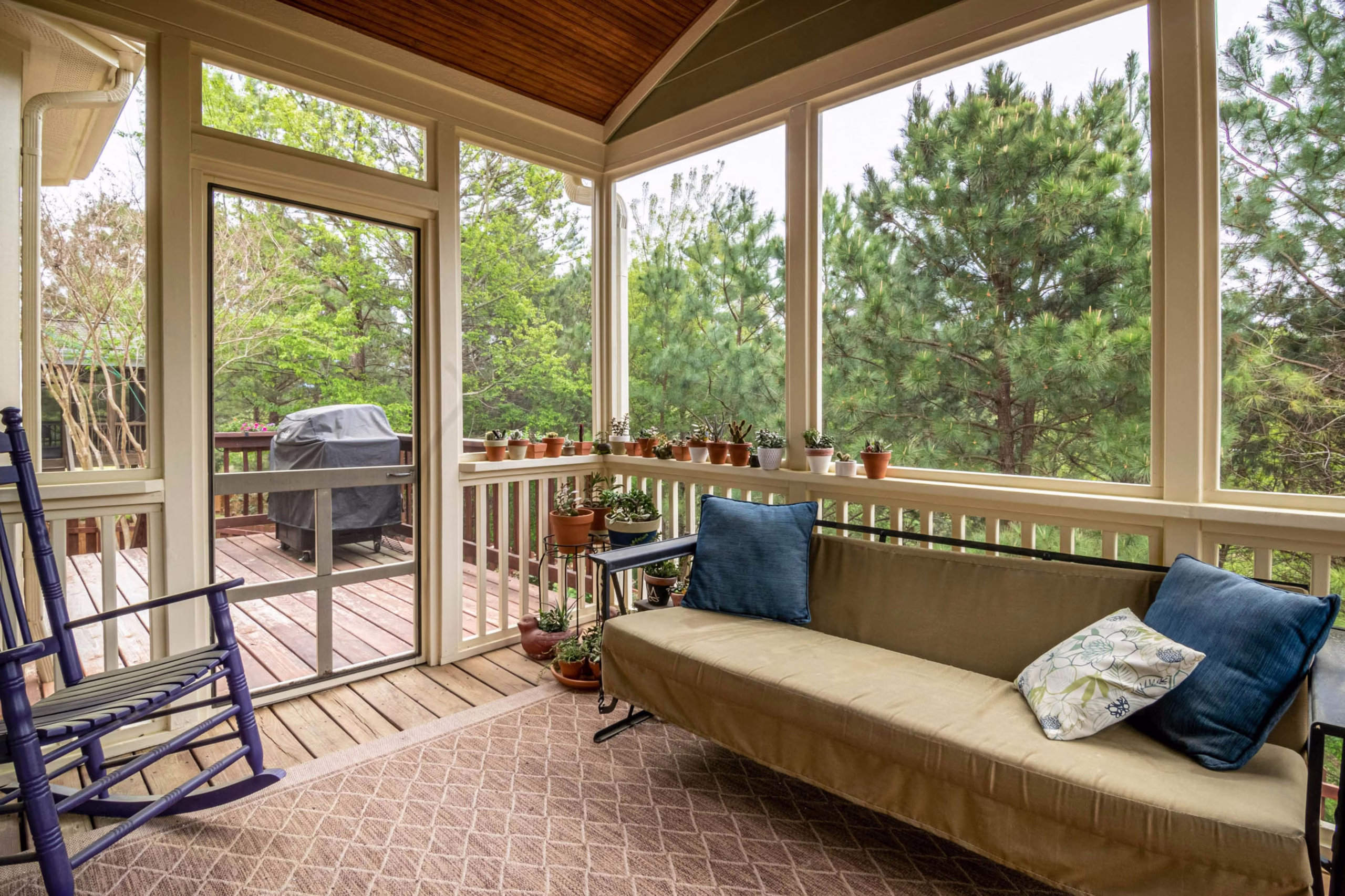 Cozy screened in porch addition with bench seating, potted plants, and natural light, creating a quiet retreat planned by a remodeler College Station families choose.