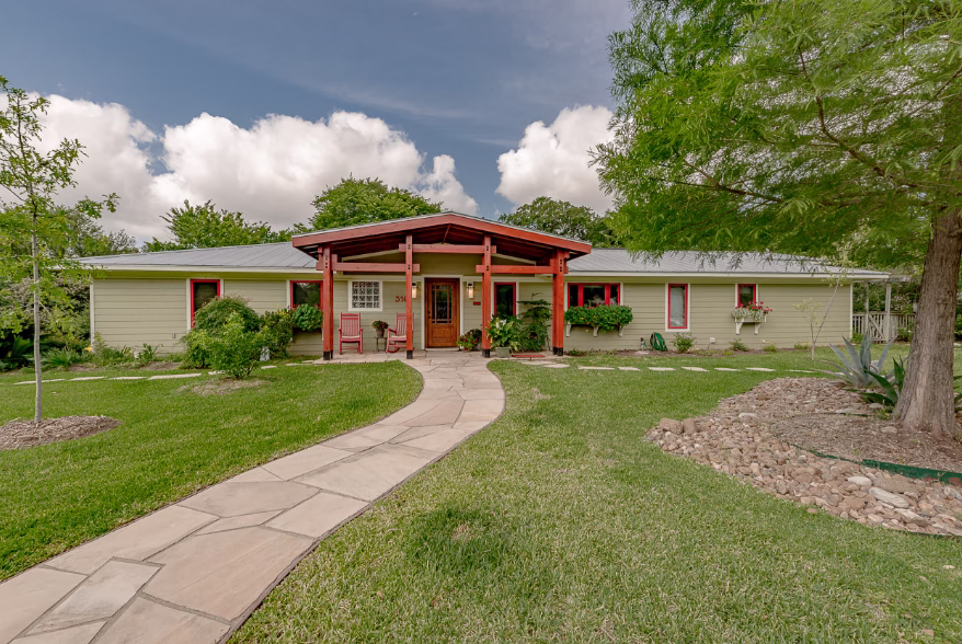 Single-story home with light-colored siding and standing seam metal roofing showing benefits of metal roofing in a warm climate