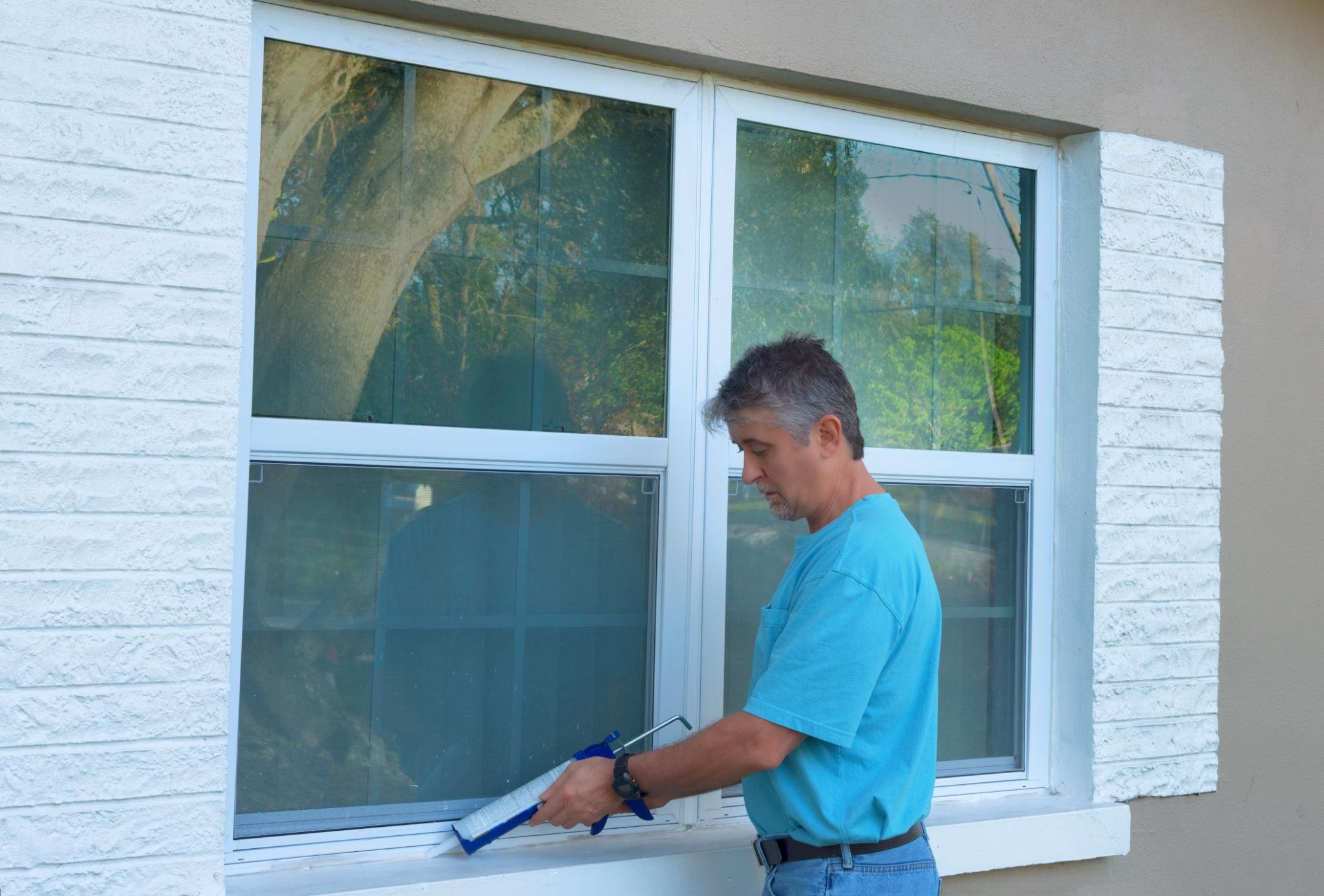 Homeowner applying caulking around a window frame to improve sealing, an important step in a home inspection checklist and home envelope inspection before remodeling