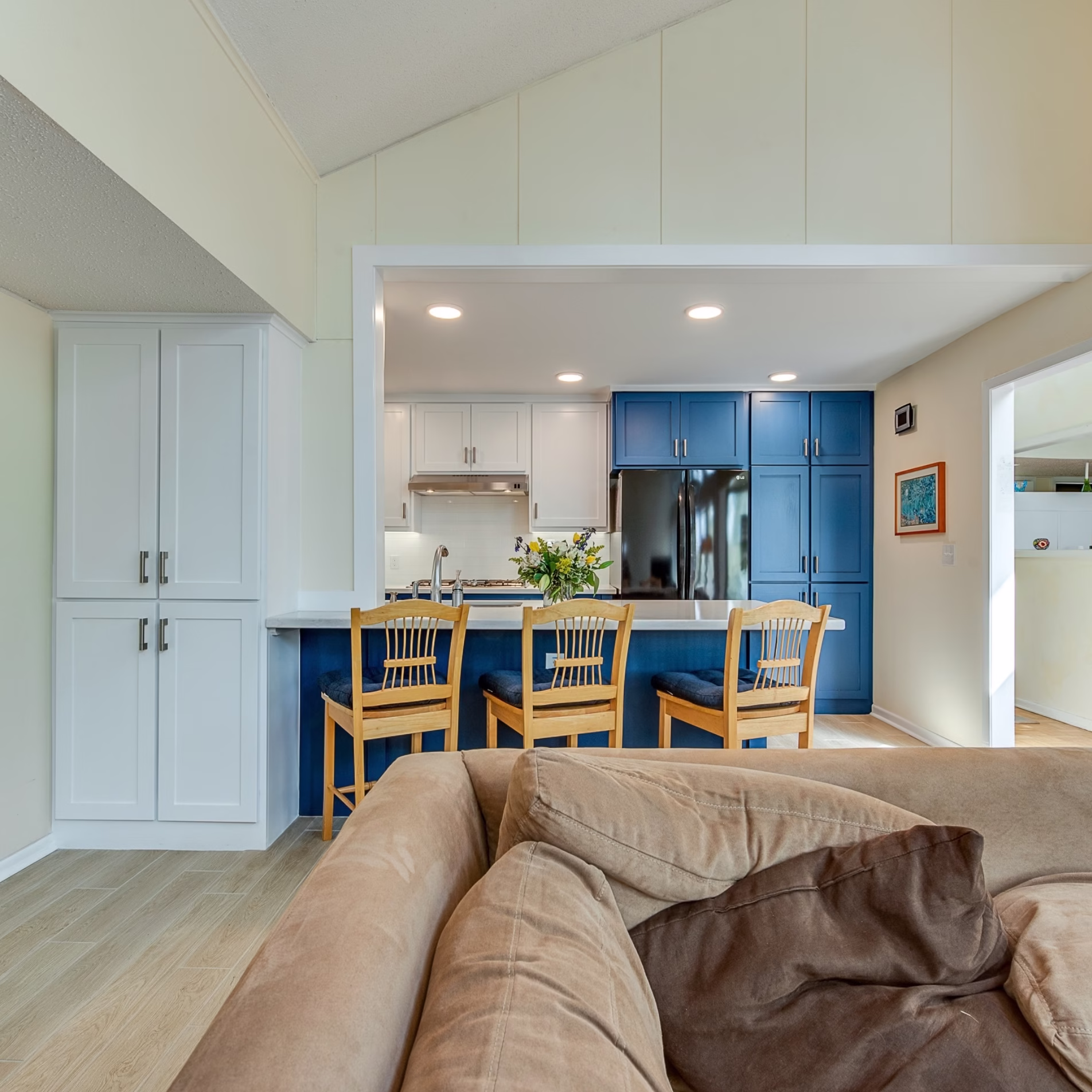 View from the family room into the remodeled kitchen showing the enlarged opening, bar seating, and new cabinetry.