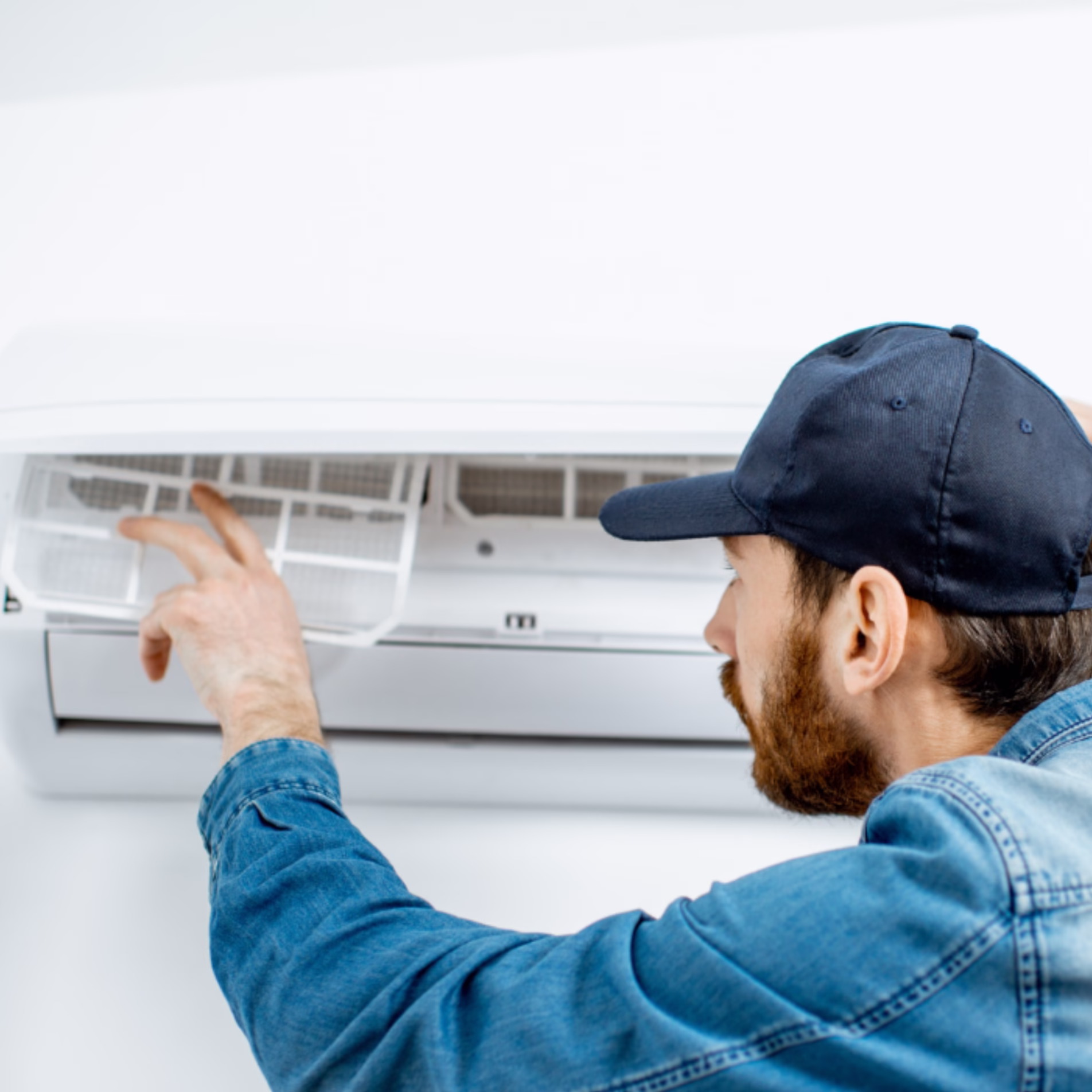 Home maintenance technician checking the filter inside a wall-mounted air conditioning unit