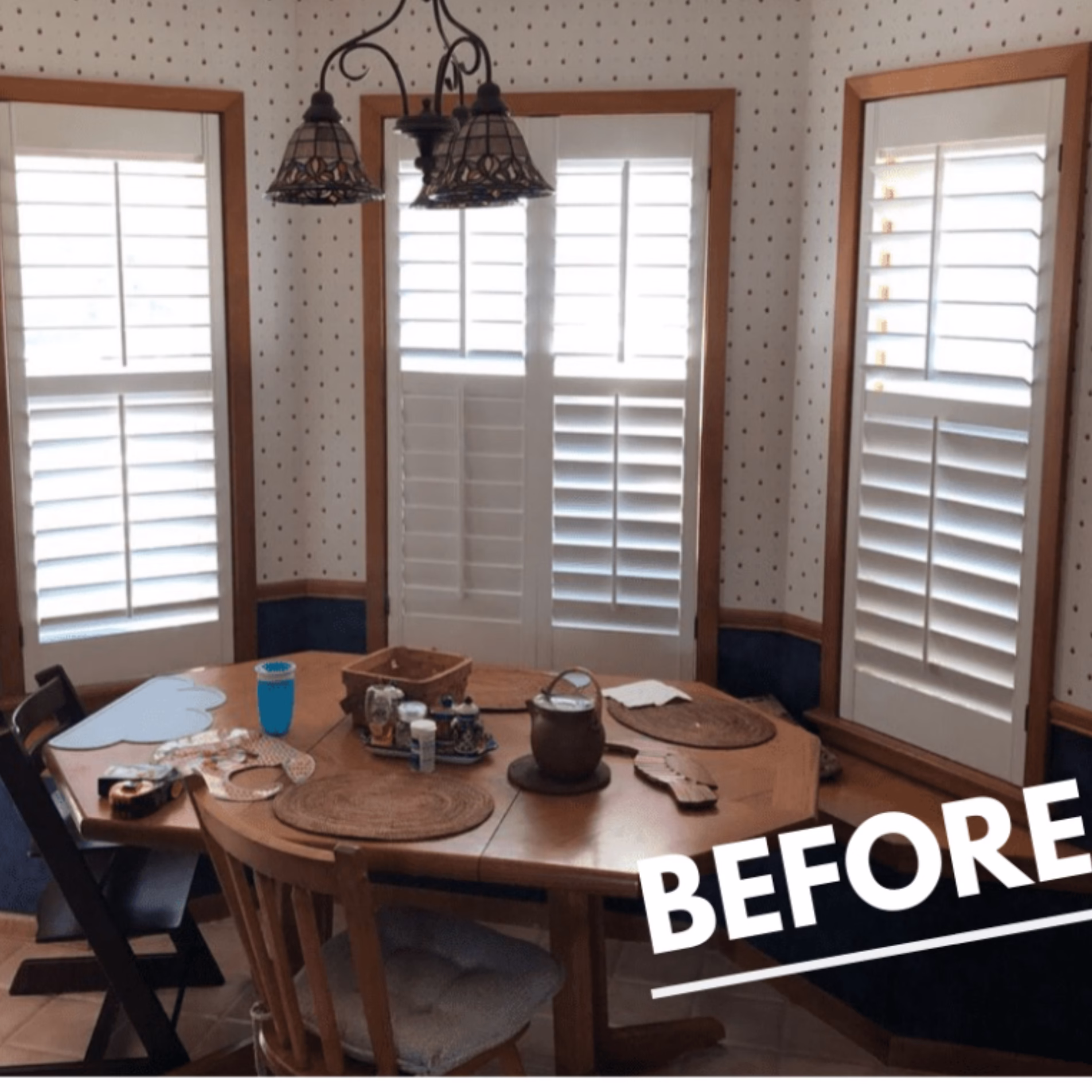 Original kitchen breakfast nook with a wooden dining table, patterned wallpaper, dark wood trim, and plantation shutters.