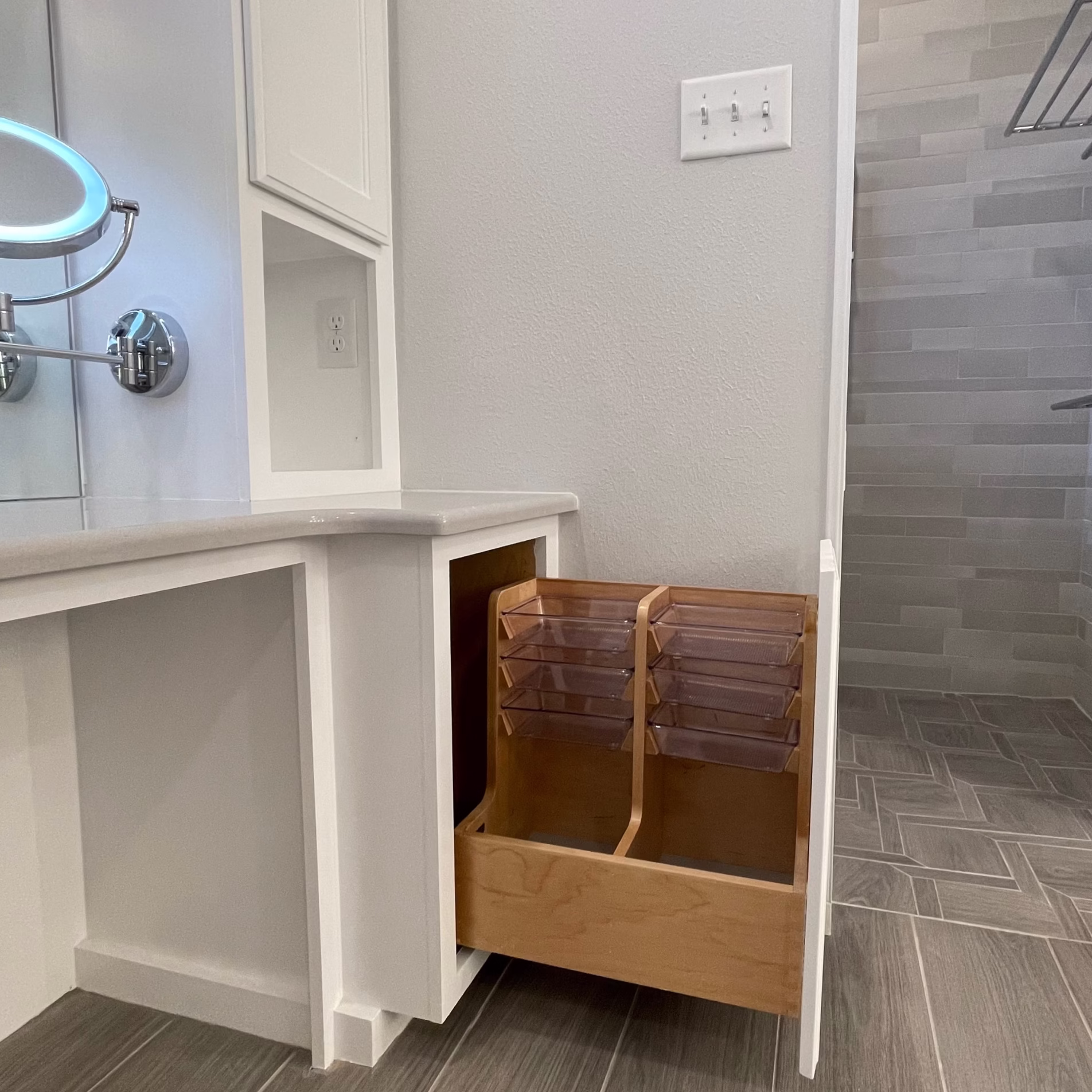 Custom pullout bathroom cabinet with multiple organizer trays for storing grooming products and everyday essentials.
