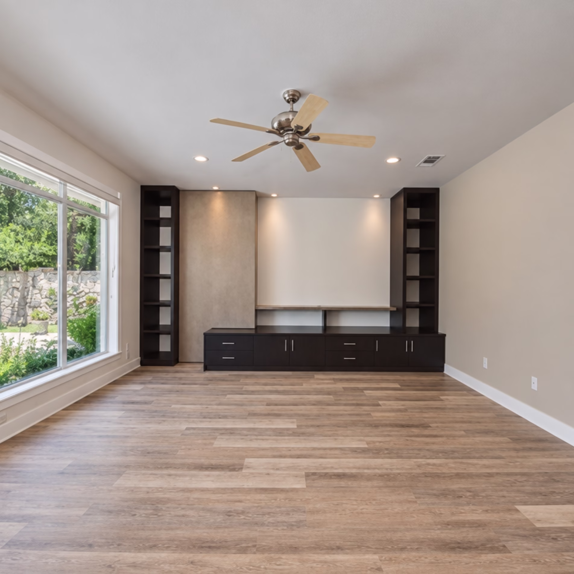 Custom living room storage wall with tall open shelving, lower cabinets, drawers, and a concealed storage door.