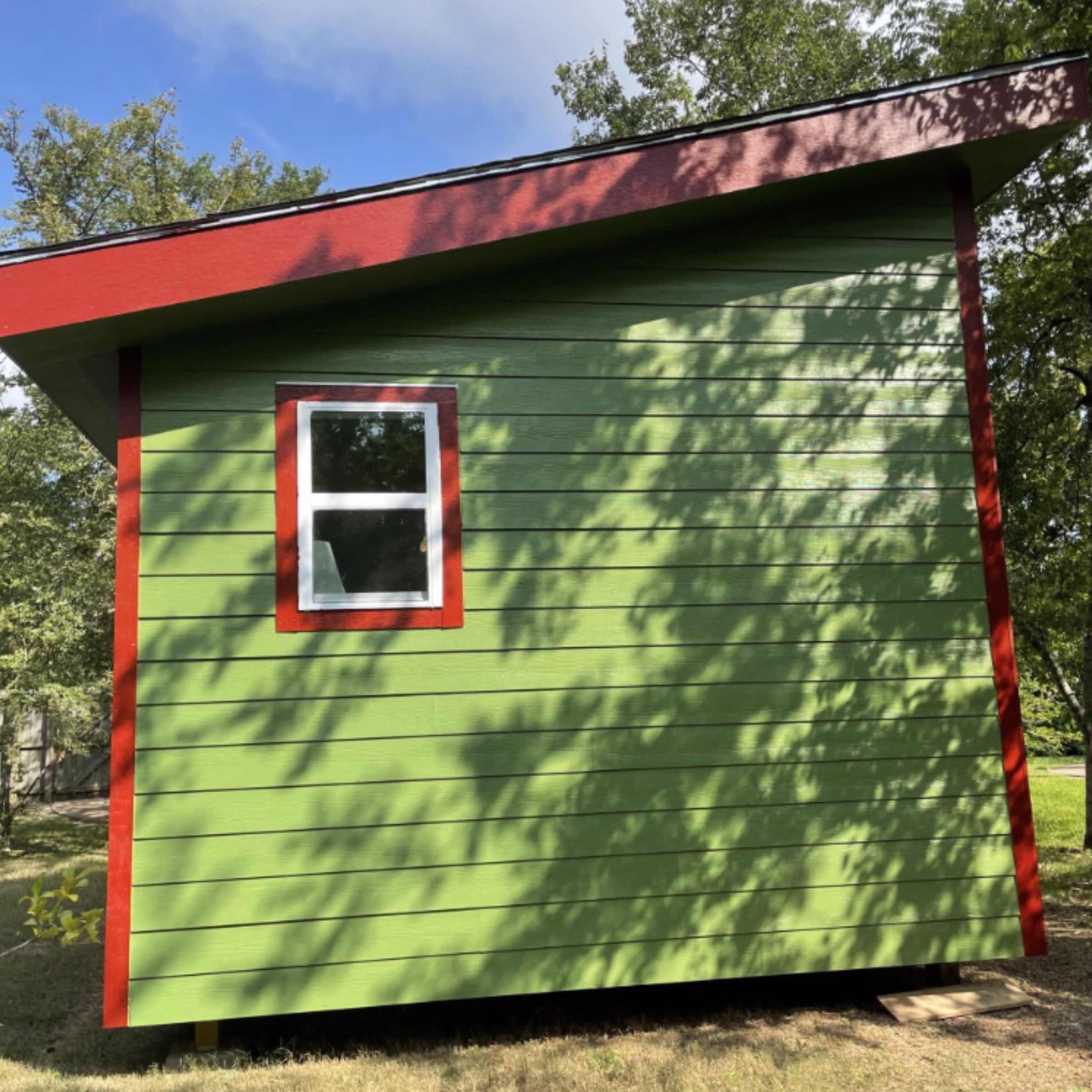 Side view of the detached backyard office showing its upward-sloping roofline and large overhang.
