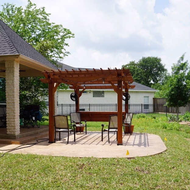 Outdoor living addition in College Station connecting the existing covered patio with a new stamped concrete patio and cedar pergola.