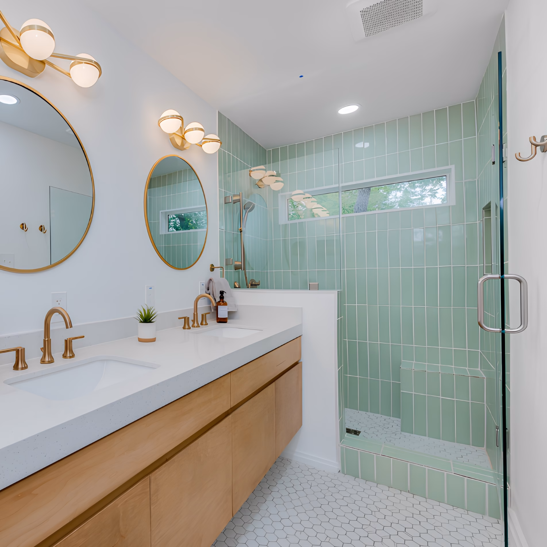 Bathroom with mint green shower tile, gold-toned faucets and mirror frames, matching vanity lights, and silver shower door hardware.