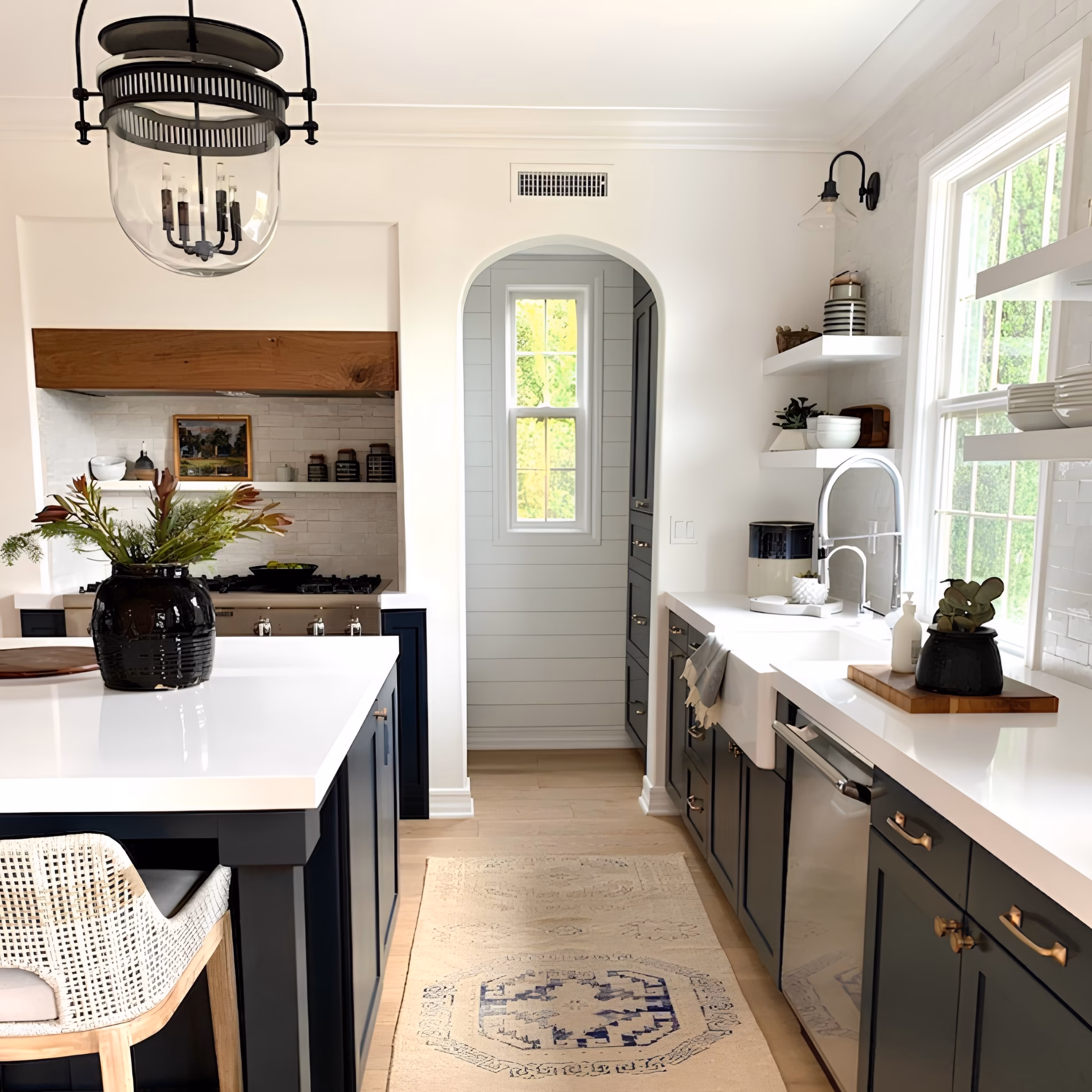 Kitchen with dark cabinetry, black pendant lighting, silver faucet, and brass cabinet hardware showing multiple metal finishes.