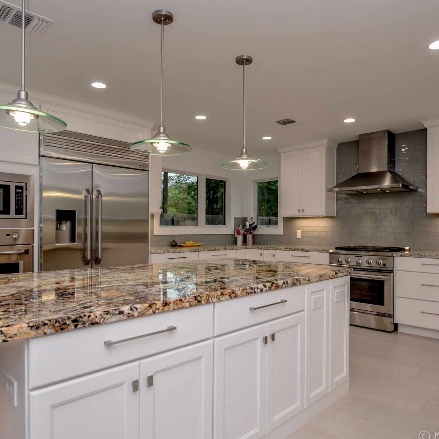 Polished granite countertop with natural gold, black, and cream veining on a large kitchen island with white cabinetry.
