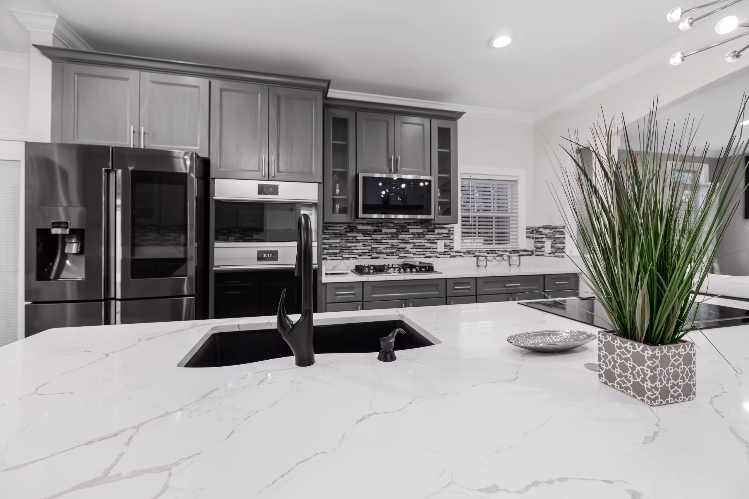 White marble countertop with subtle gray veining, black undermount sink, and gray cabinetry in a contemporary kitchen.