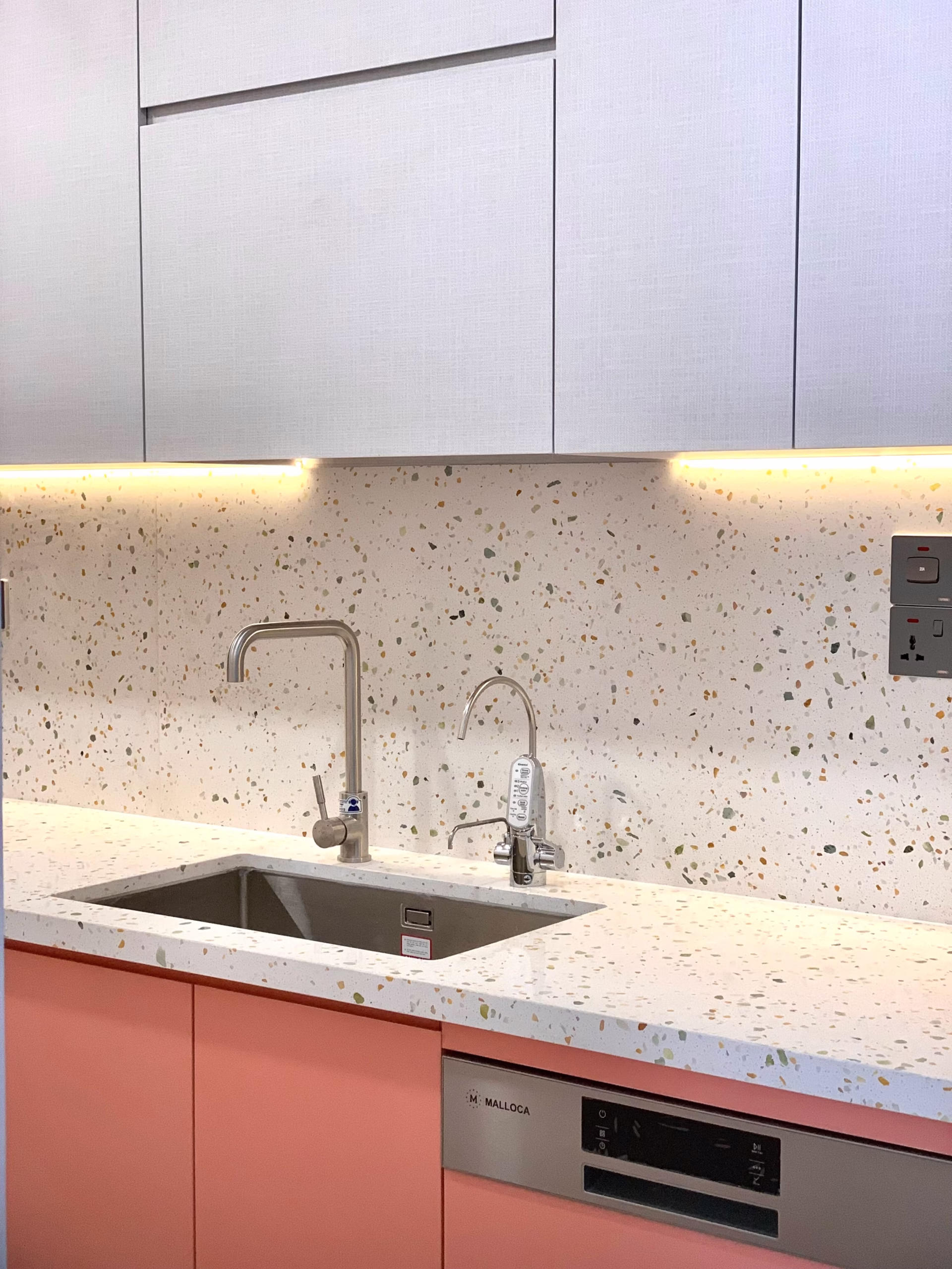 White recycled glass countertop with multicolored terrazzo-style flecks, integrated sink, and matching full-height backsplash in a modern kitchen.