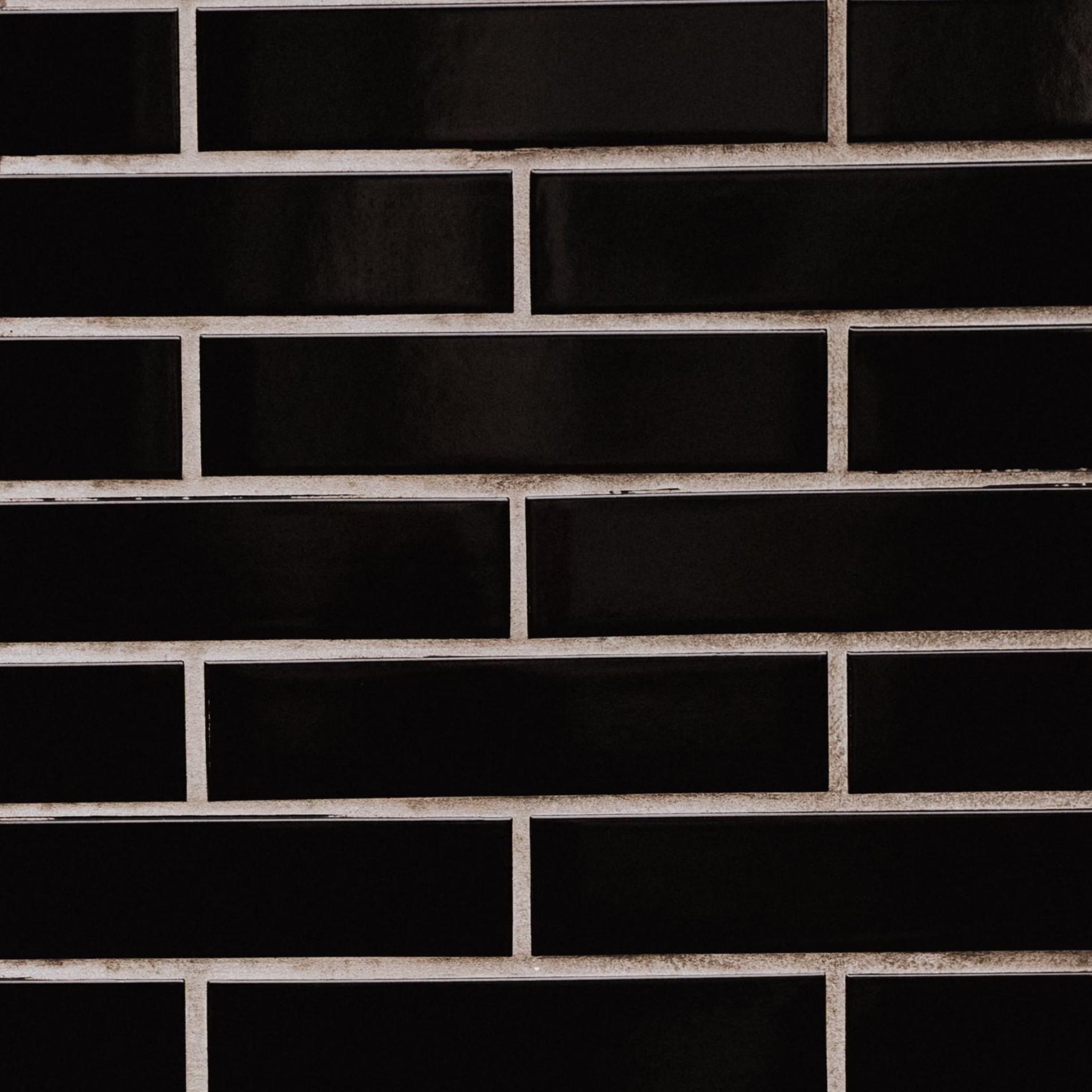 Black subway tile with contrasting light grout that clearly defines each rectangular tile.