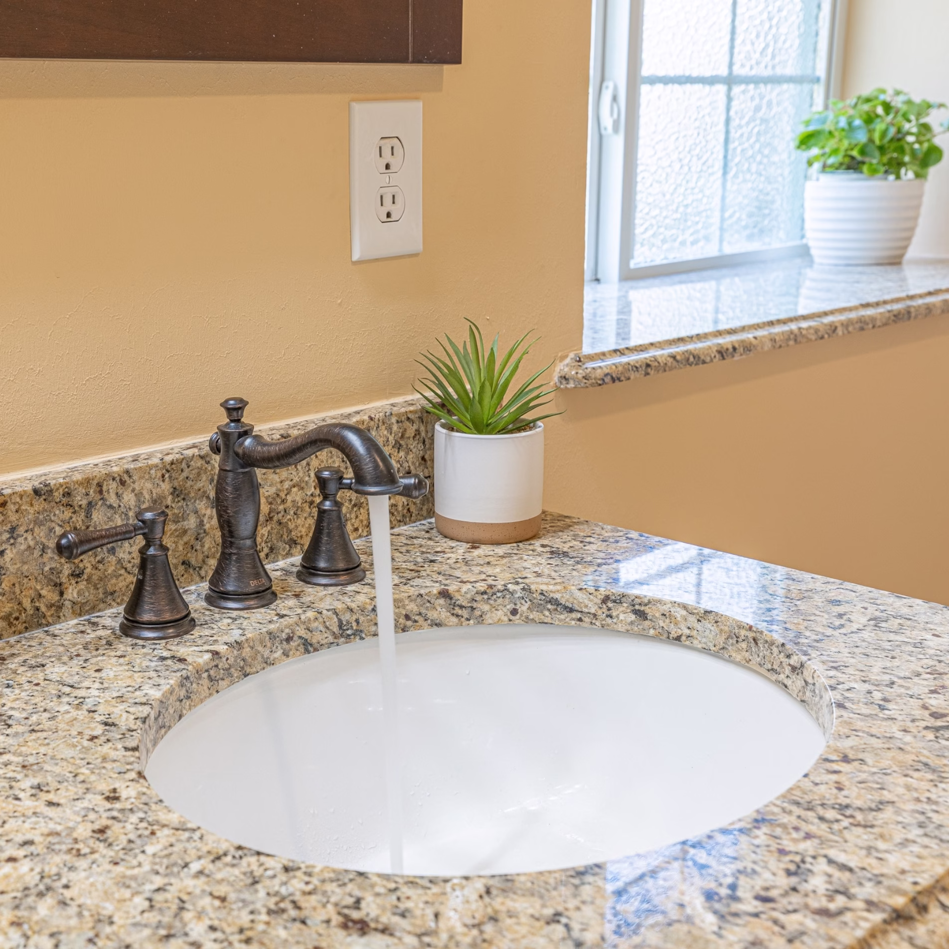 Italian-inspired primary bathroom remodel with granite vanity, warm beige walls, and an accessible tiled shower