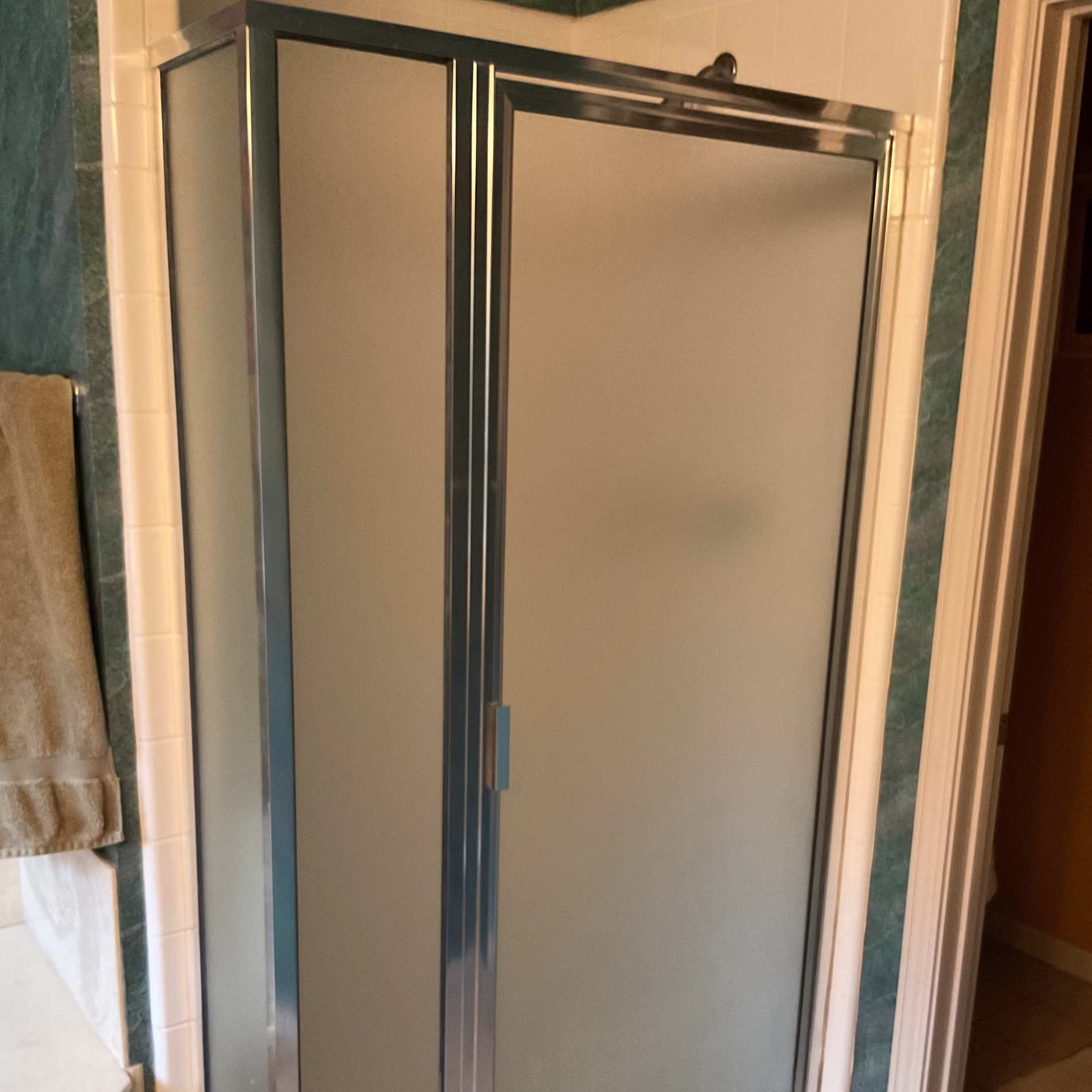 Small original prefabricated shower with frosted glass enclosure beside the corner bathtub