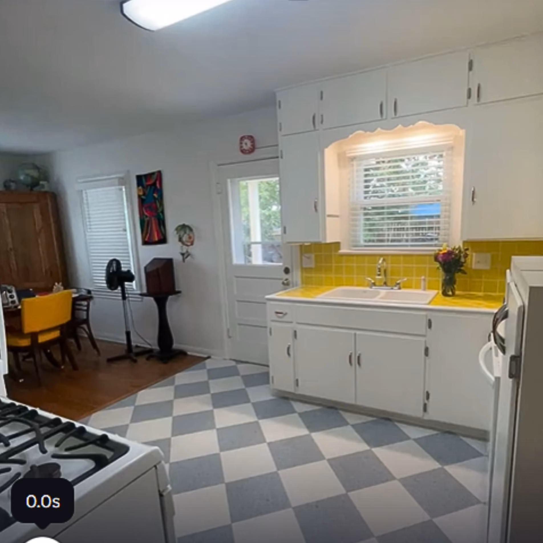Open connection between remodeled kitchen and dining room, featuring yellow tile countertops, white cabinets, and checkerboard flooring.