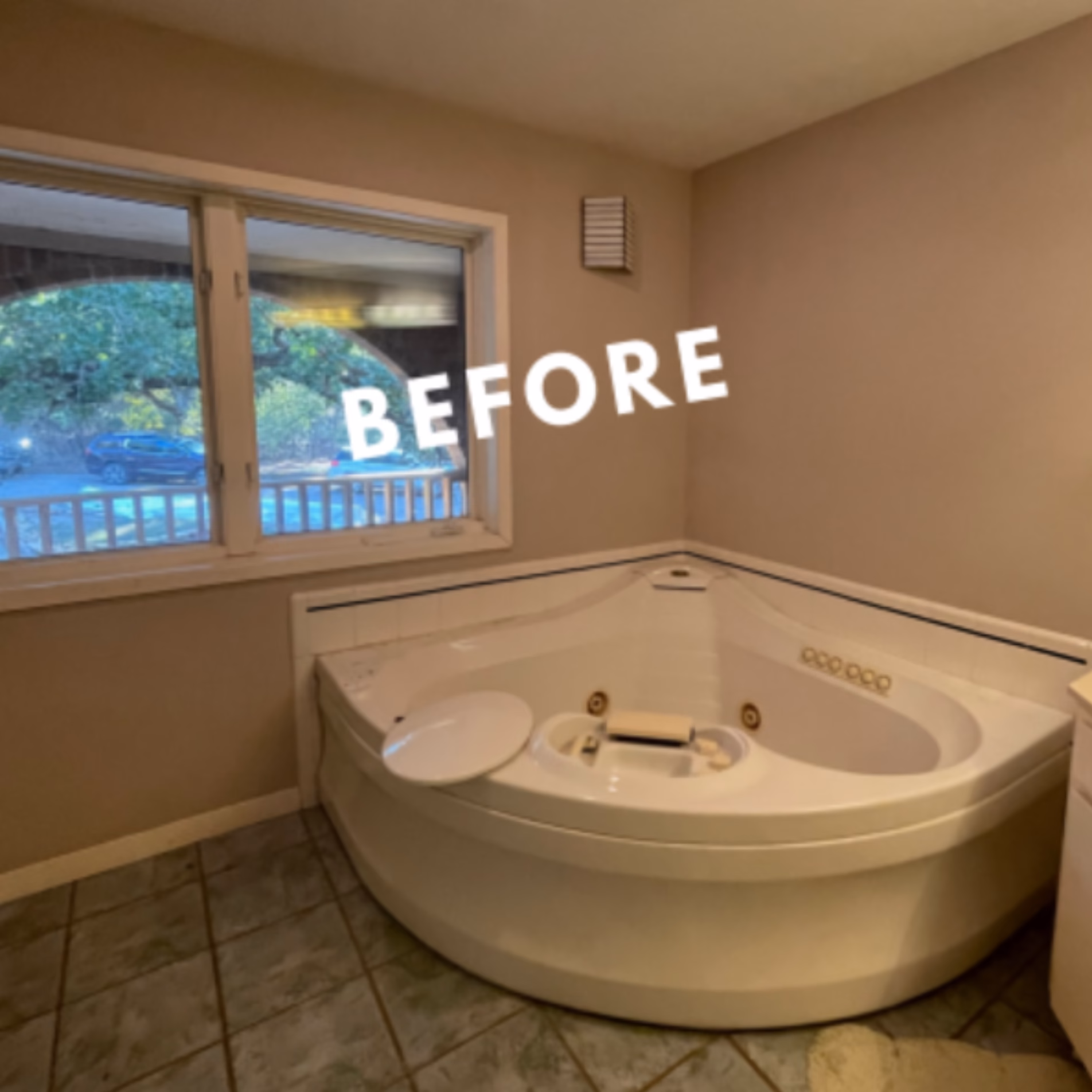 Original corner jetted bathtub with white tile surround and gray floor tiles before the Gibb Estates bathroom remodel.
