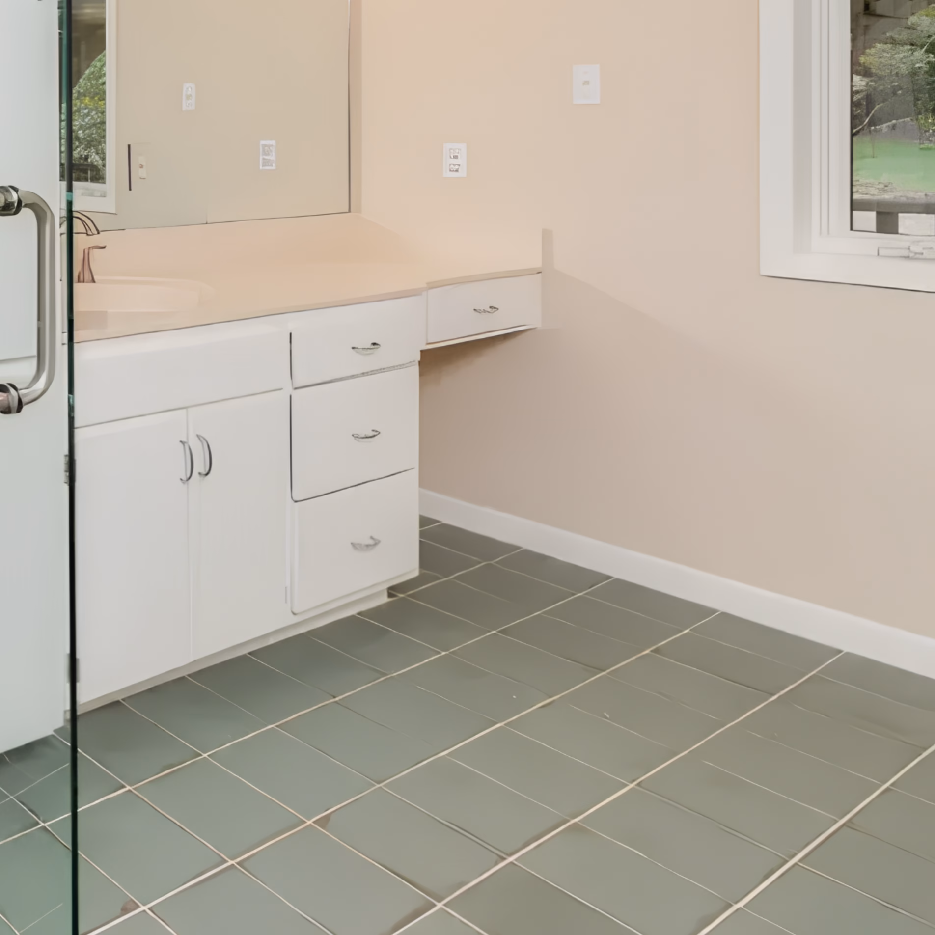 Matte green bathroom floor tiles with contrasting grout lines beside a white vanity in the remodeled Gibb Estates bathroom.