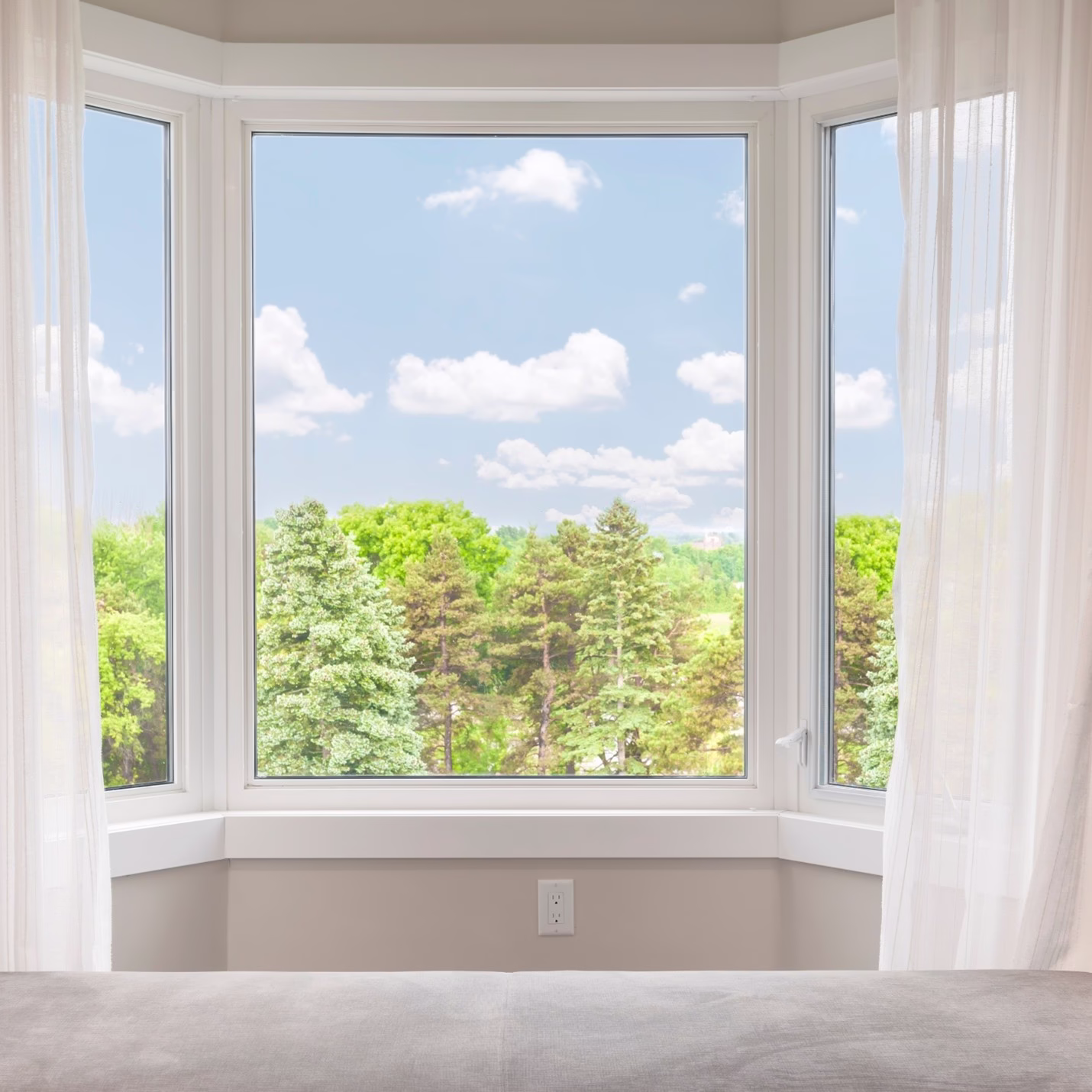 Bay window framing views of trees and sky, emphasizing natural light and visual transitions between the home interior and the outdoors