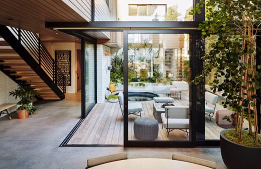 Transitions in home design shown through a seamless connection between interior living space and an outdoor patio using large glass doors