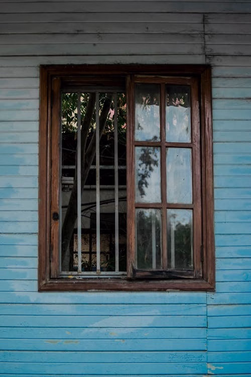 Weathered exterior siding and window frame showing deterioration caused by long-term moisture exposure.