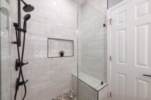 Glass enclosed walk-in shower with built-in bench and wall niche installed during a guest bathroom makeover renovation