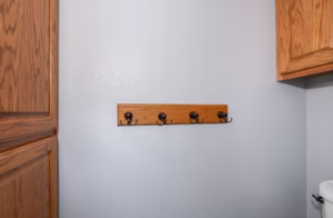 Bathroom storage wall with mounted hooks and updated finishes included in a functional guest bathroom makeover