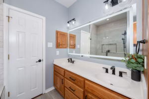 Double sink vanity with updated lighting, mirrors, and fixtures as part of a two guest bathroom makeover project