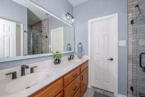 Updated bathroom vanity with quartz countertop, matte black faucet, and illuminated mirror from a modern bathroom makeover