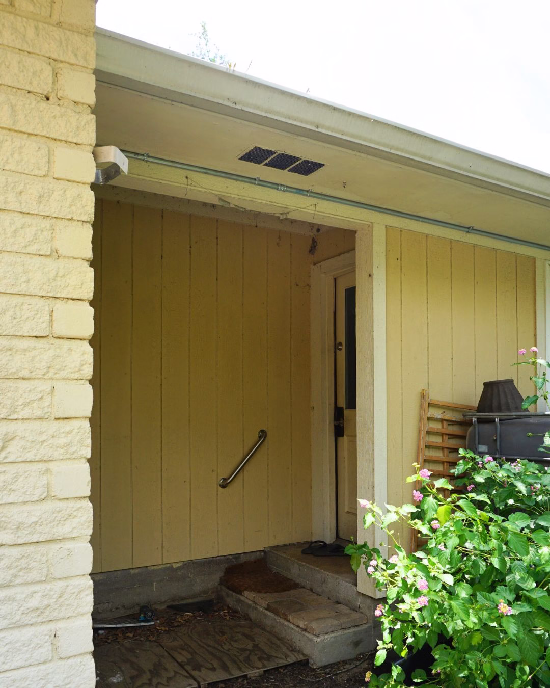 Exterior entry with small concrete steps before modifications during an aging in place renovation in Bryan–College Station.