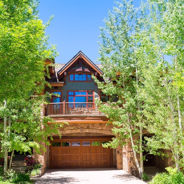 Residential home with brick and wood exterior materials shaded by trees, showing how design choices can reduce heat exposure in hot humid climates.