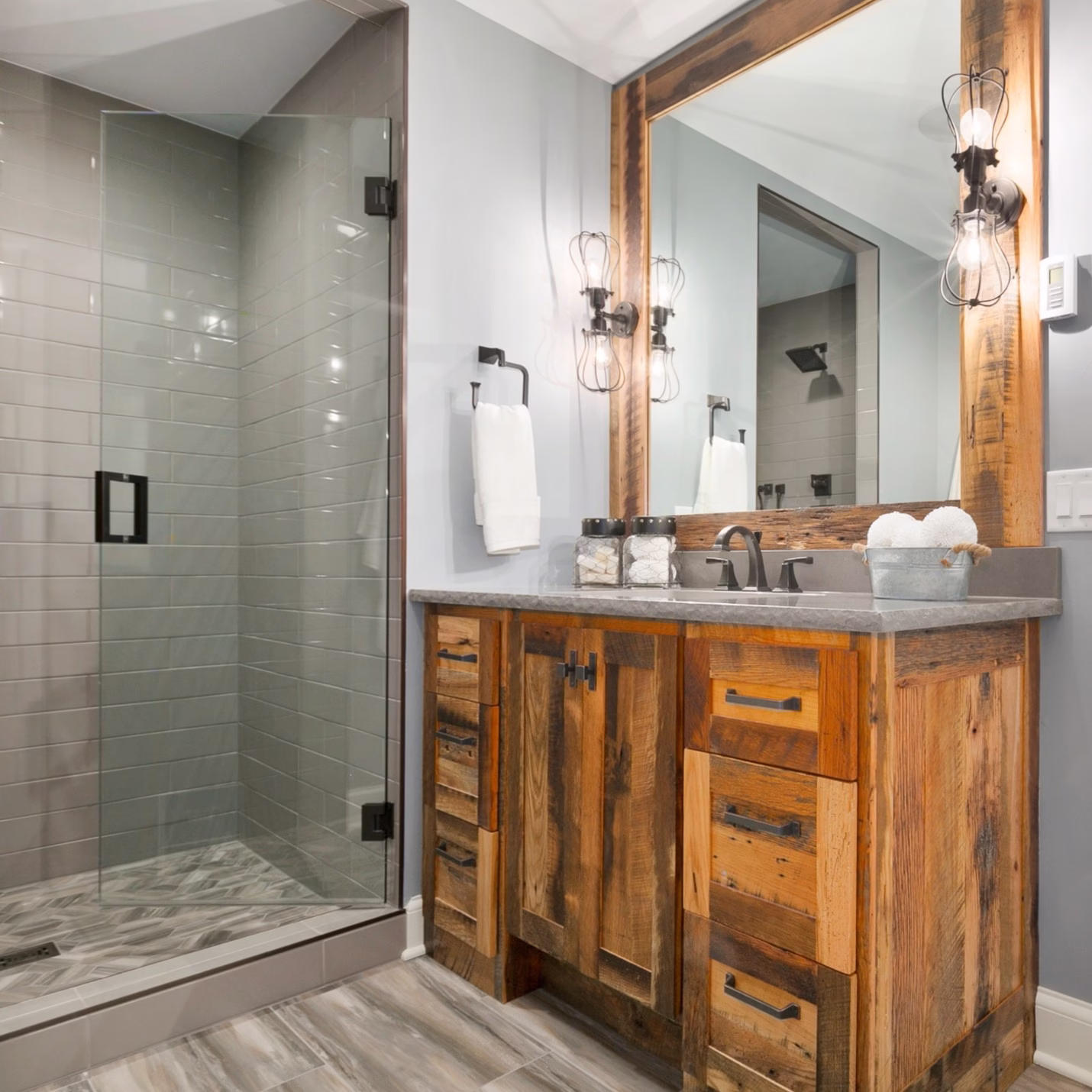 Bathroom remodel featuring a custom wood vanity and glass shower enclosure demonstrating balance between function and long term comfort