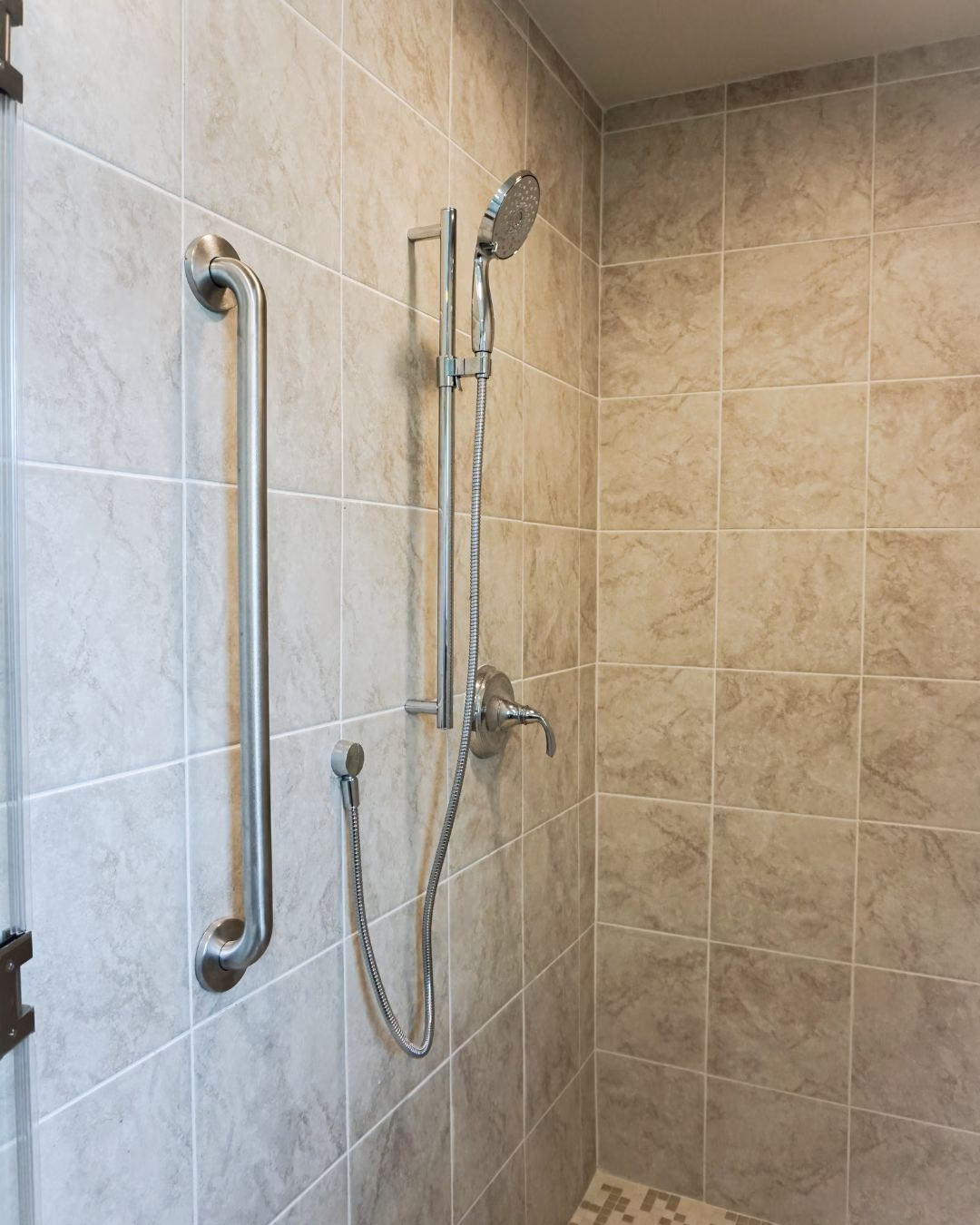 Adjustable hand shower and grab bar installed as part of an aging in place renovation for improved bathing accessibility.
