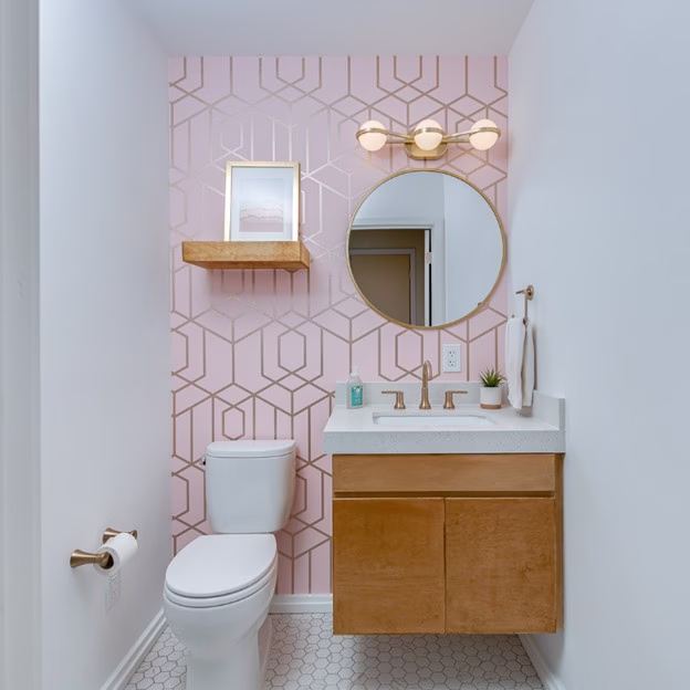 half bathroom from mid century modern remodel College Station featuring pink geometric wallpaper, floating wood vanity, and brass lighting fixtures