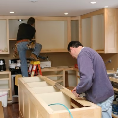 Builders installing kitchen cabinetry during a home remodel in College Station with focus on craftsmanship and coordination