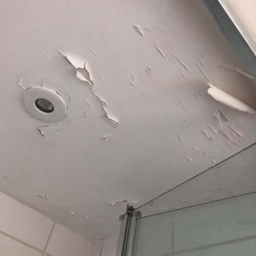 Peeling ceiling paint caused by moisture issues in a poorly completed bathroom remodel highlighting risks of choosing the wrong contractor