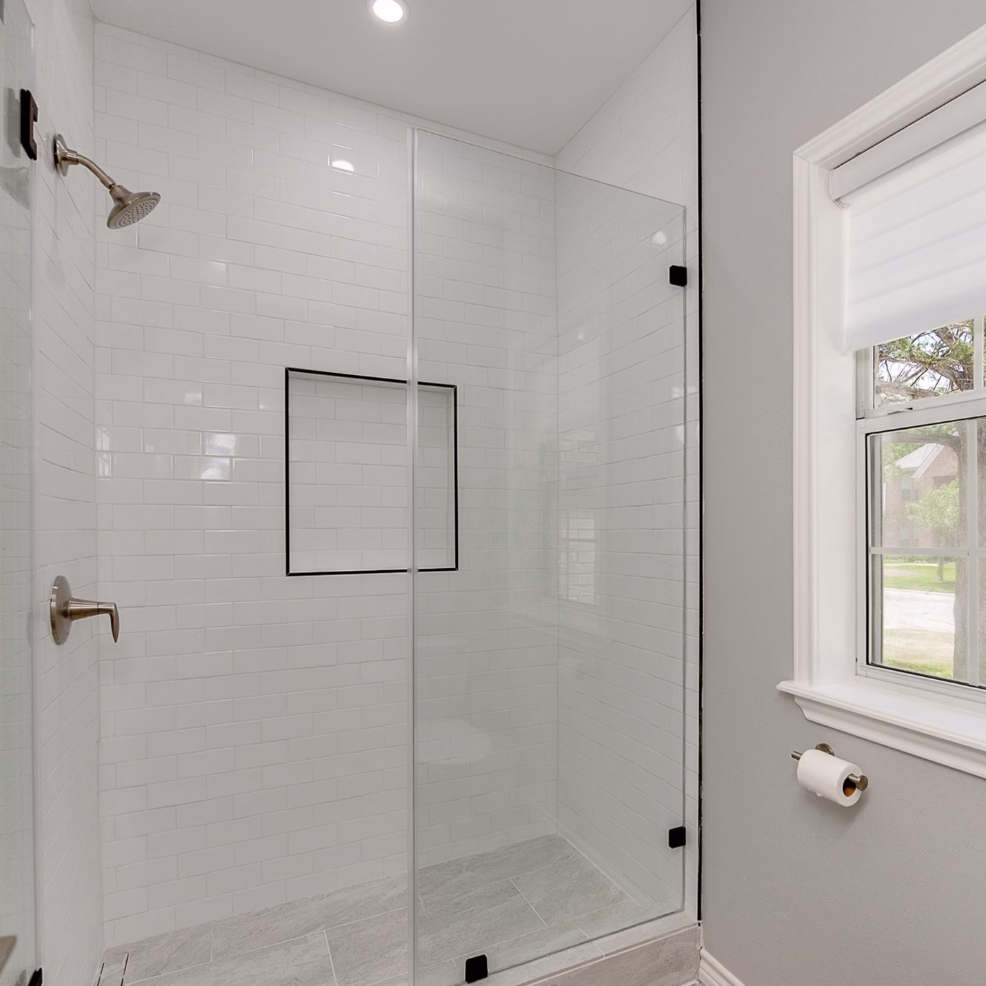 Bathroom Remodel Considerations walk-in shower with glass enclosure, white tile walls, and built-in niche for practical daily use