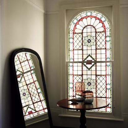 Historic stained glass window with reflective mirror and soft neutral walls demonstrating interior color planning, light reflection, and how color can reinforce architectural character in a home remodel in College Station.
