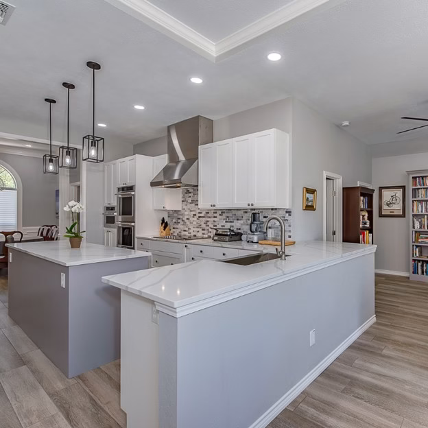 Bright remodeled kitchen with white cabinetry, quartz surfaces, and open connection to the dining room during this aging in place remodel