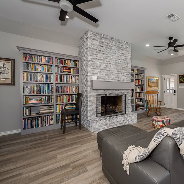 Living room after the modern whole home renovation with whitewashed brick fireplace, custom bookshelves, and improved openness throughout the space