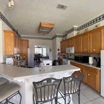 Traditional kitchen peninsula and oak cabinetry before a whole home renovation Bryan TX project that modernized the space while improving everyday usability.