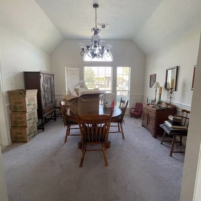 Dining room before a whole home remodel College Station project featuring original carpet, traditional chandelier, and vaulted ceiling prior to modernization.