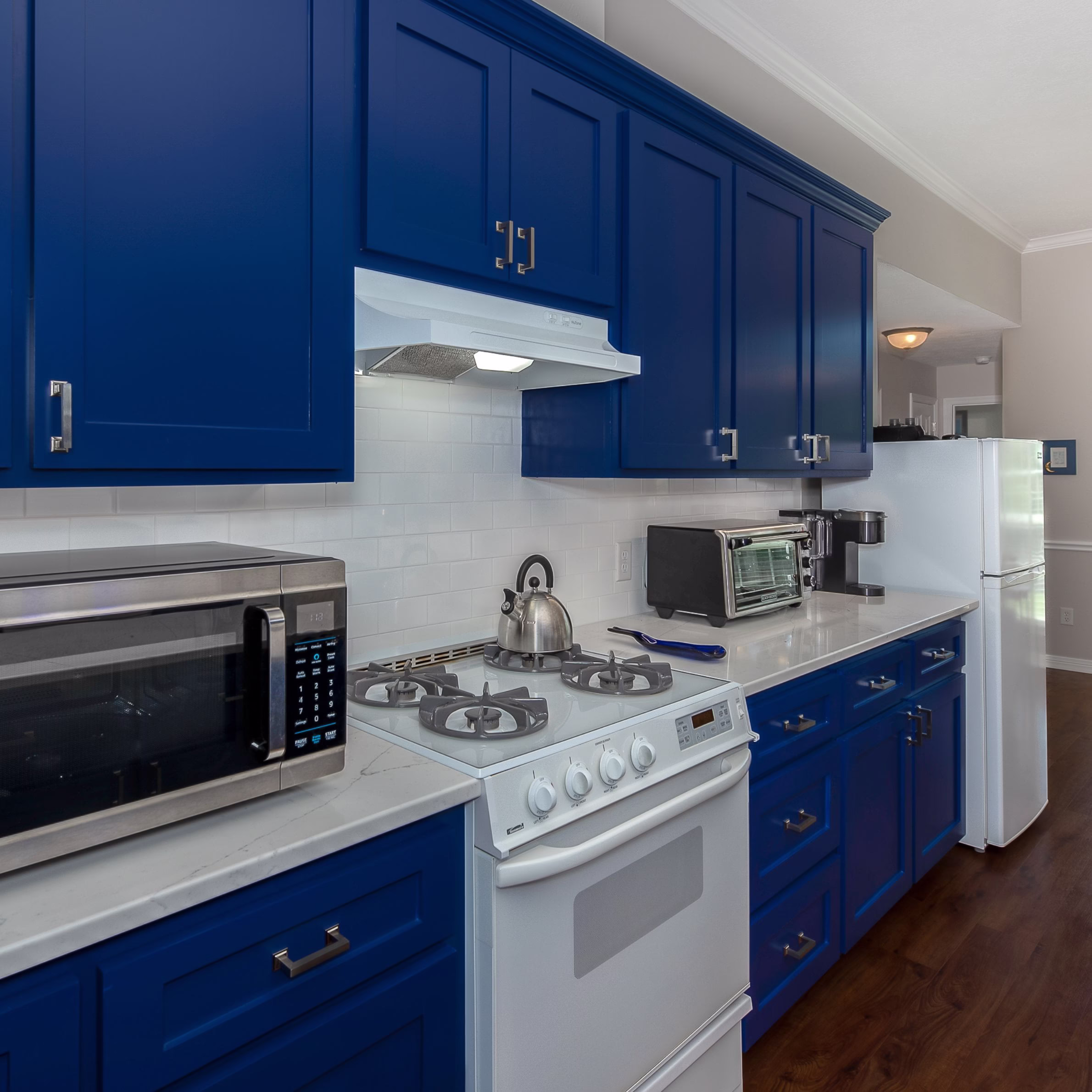 Updated kitchen with painted cabinetry, new range hood, quartz countertops, and subway tile backsplash completed during a whole home remodel College Station project.