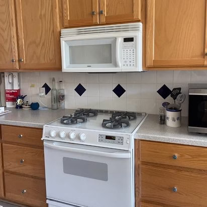 Existing kitchen with original microwave, cabinetry, and cooktop before a modern home remodel that improved function, ventilation, and updated finishes.