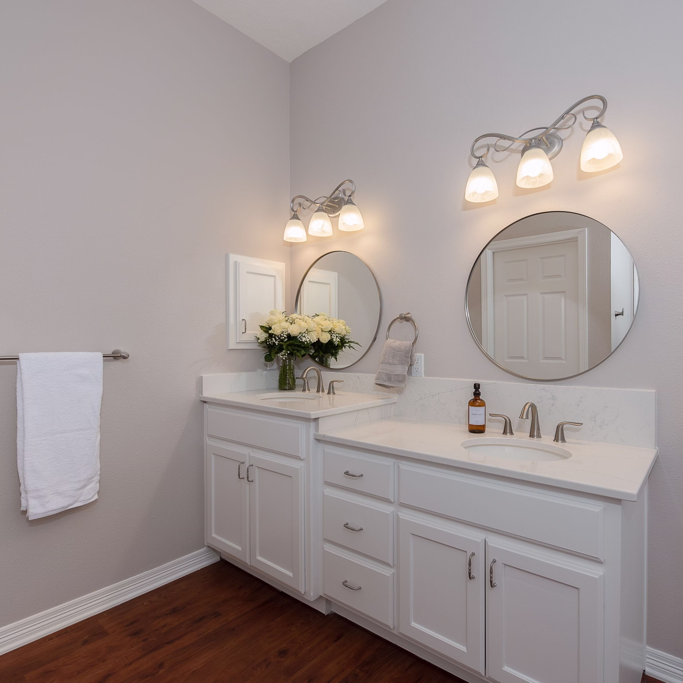 Primary bathroom vanity with quartz countertops, round mirrors, updated lighting, and painted cabinetry completed as part of an accessible bathroom remodel designed for long-term comfort.