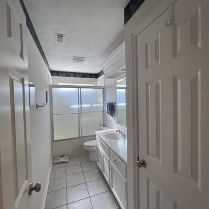 Existing primary bathroom layout before an aging in place remodel, showing narrow circulation space, enclosed shower, and traditional finishes.