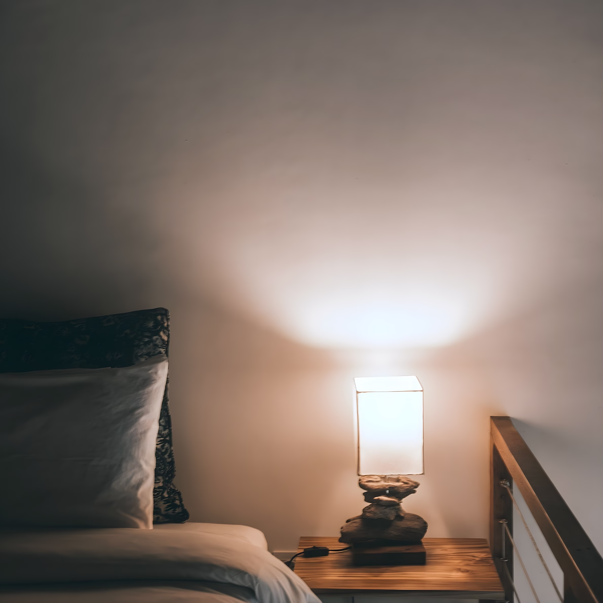 Modern bedroom with a bedside table lamp casting warm ambient light, illustrating energy-efficient home lighting and everyday residential energy use.