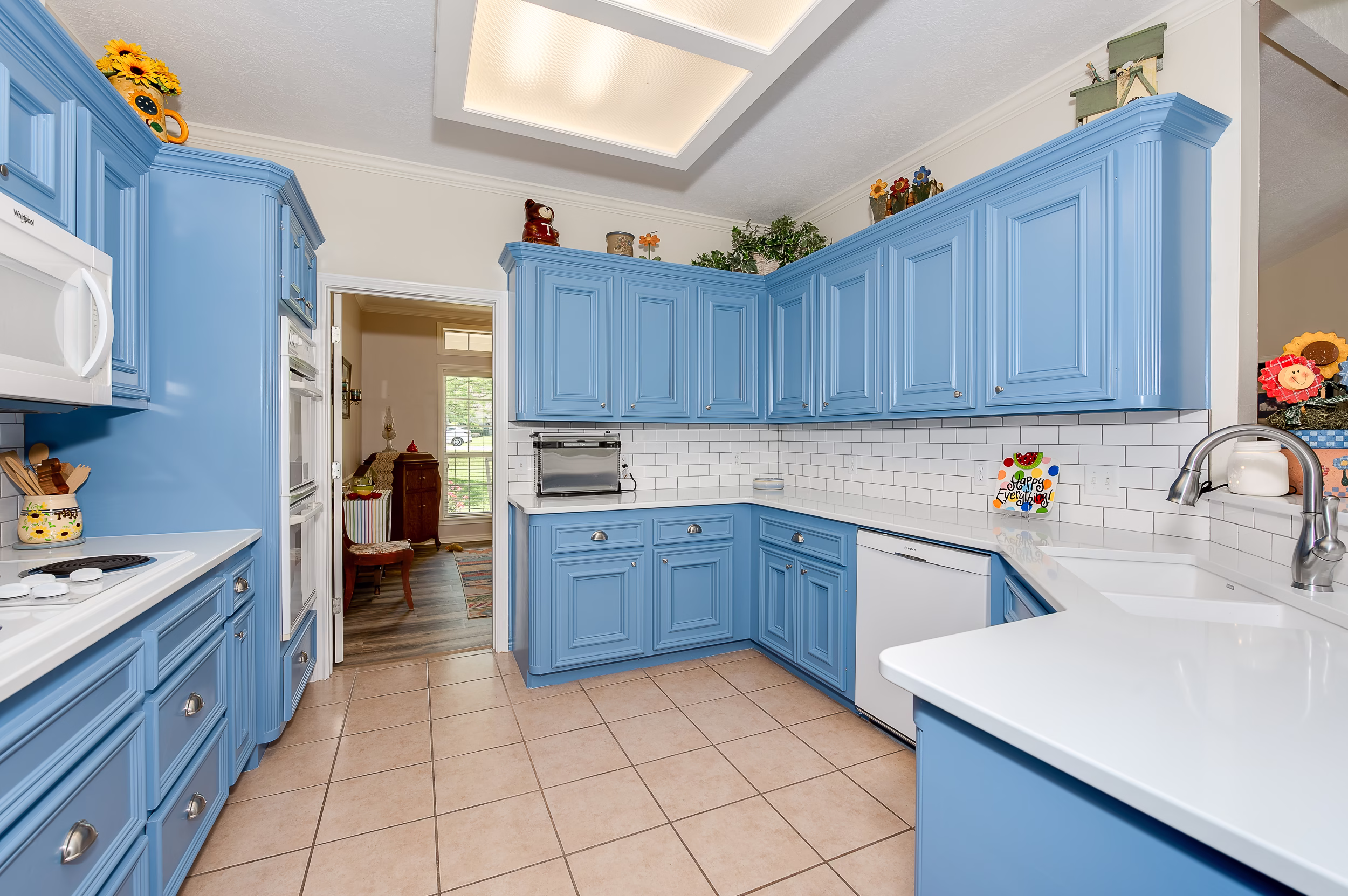 Remodeled kitchen with blue cabinets, white countertops, subway tile backsplash, updated hardware, and bright ceiling lighting.