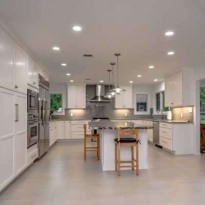 Modern white kitchen with recessed ceiling lights and layered lighting designed to improve visibility for aging-in-place home design.