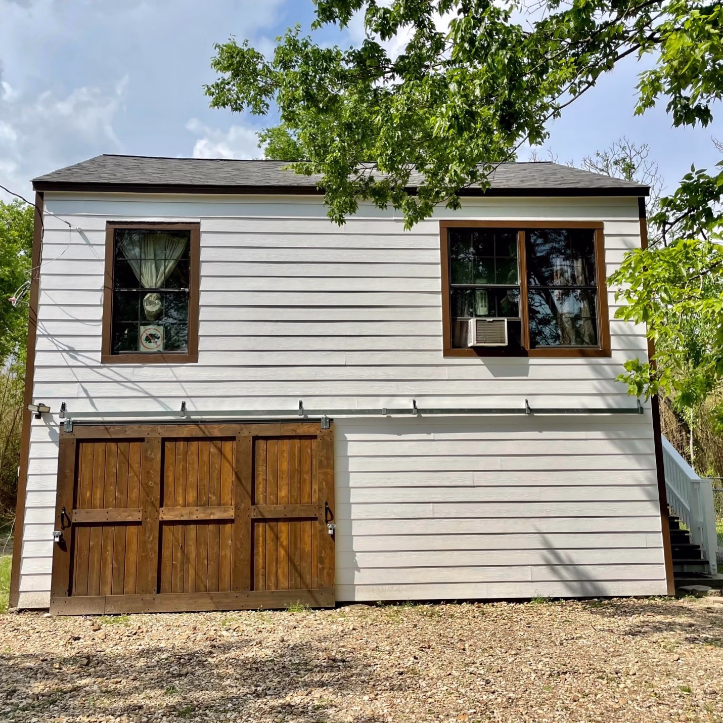Rear of the renovated guest house featuring white siding and a custom wood barn-style garage door