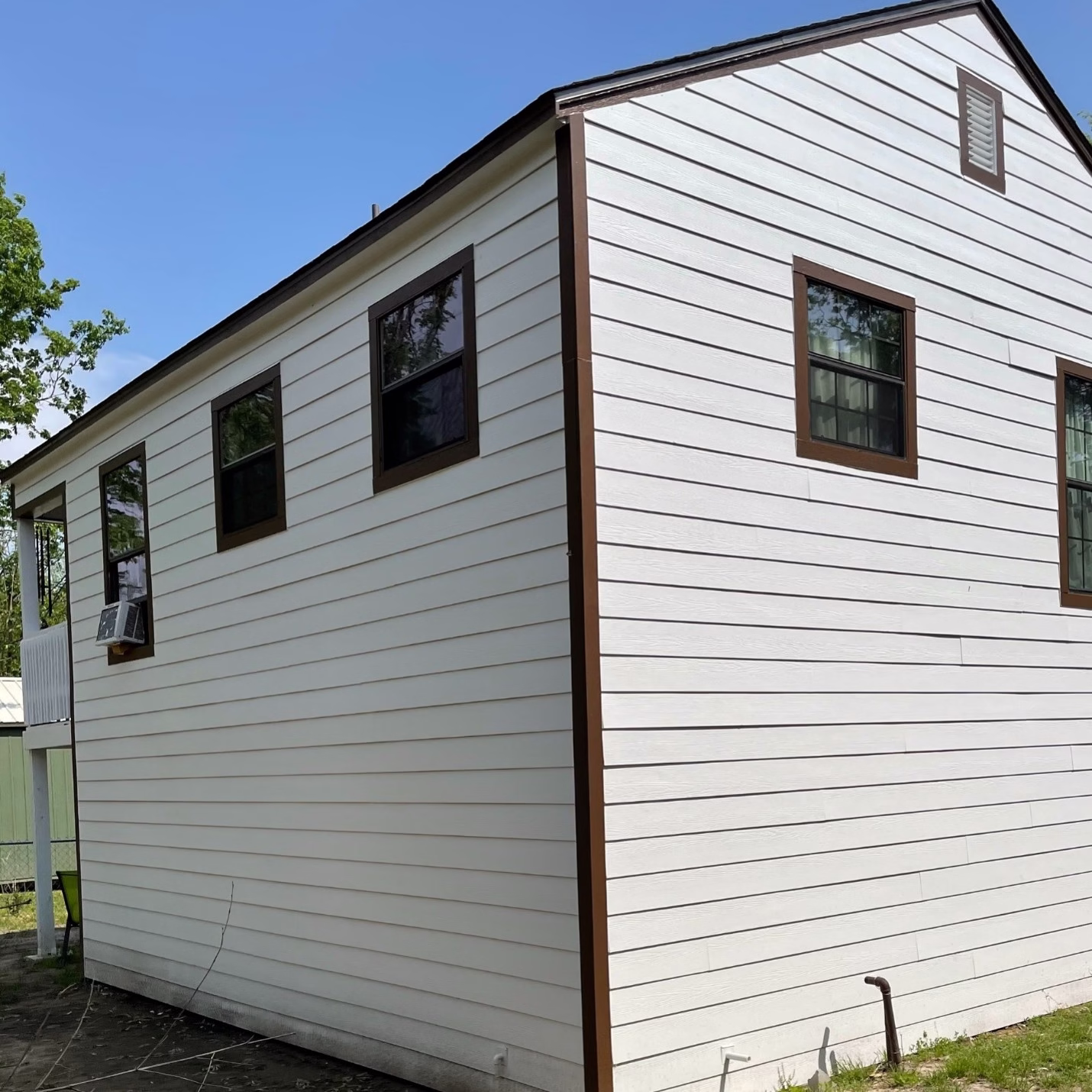 Side view of the renovated guest house featuring new white siding, dark window trim, and updated exterior finishes